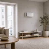 Rekuperator ścienny Mitsubishi Lossnay VL-50S2-E zamontowany na ścianie w jasnym, minimalistycznym salonie z dużym oknem