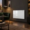 Biały grzejnik elektryczny Radialight Aetherea 15 na ciemnej ścianie salonu, przy zielonym fotelu, wieczorem